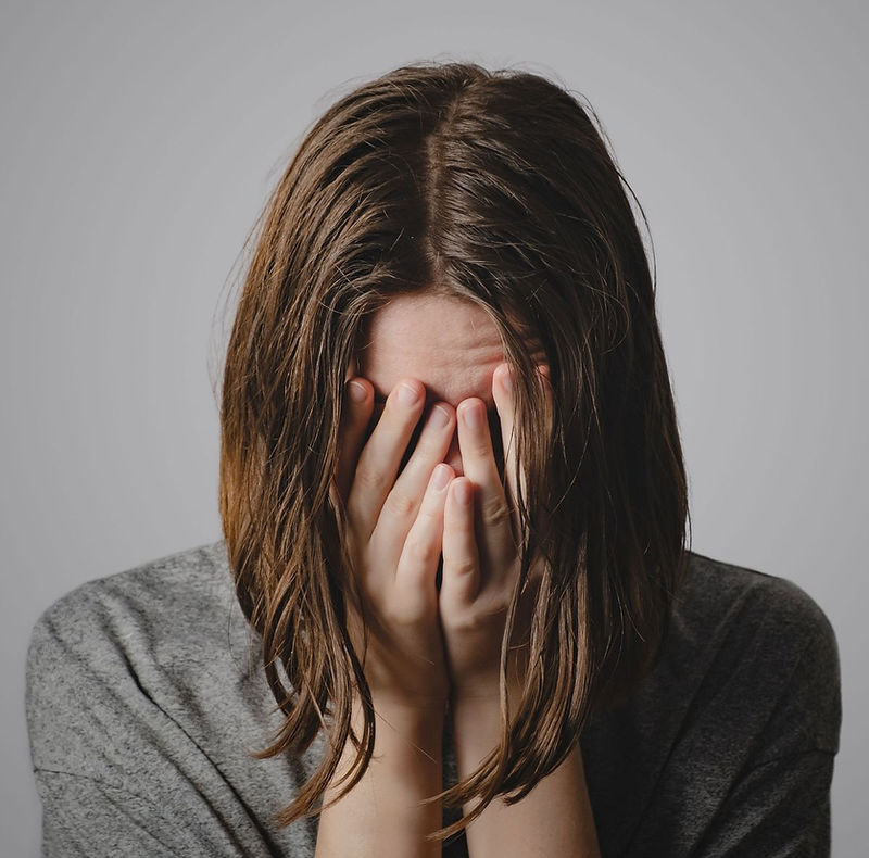 A person with their hands covering their face
